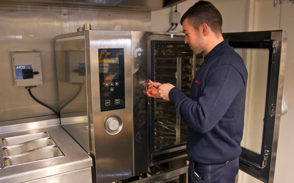 An engineer fixing a piece of kitchen equipment