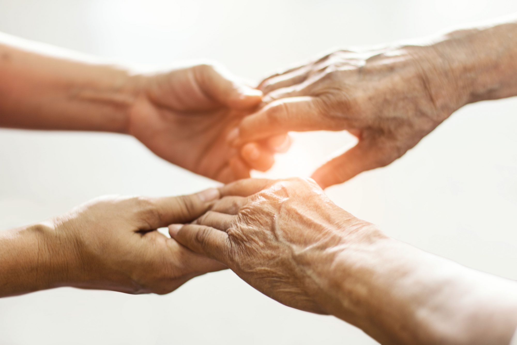 An elderly pair of hands in those of someone younger