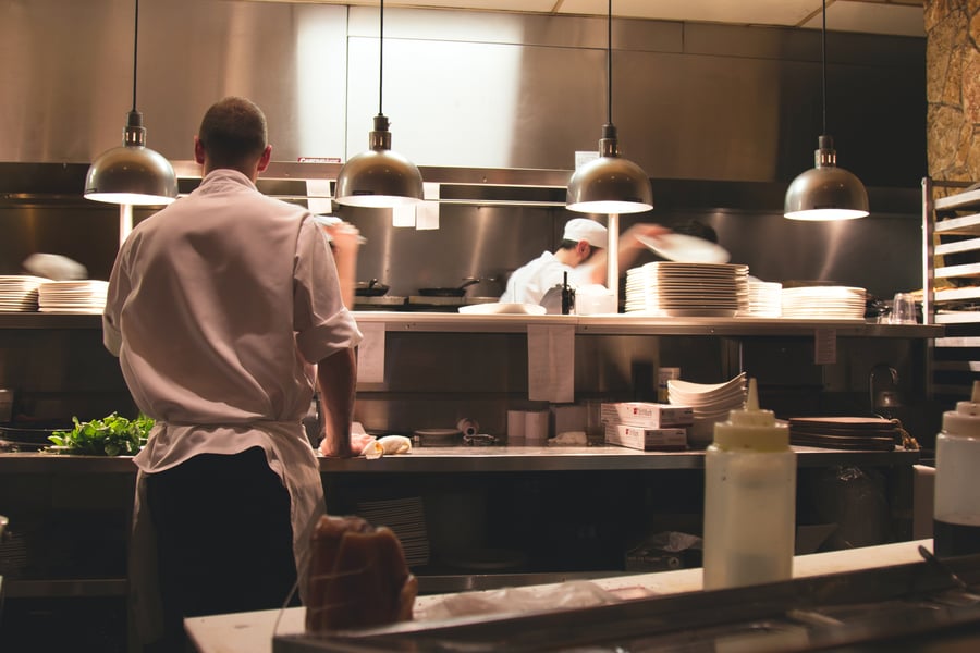 A chef waiting at the pass for dishes